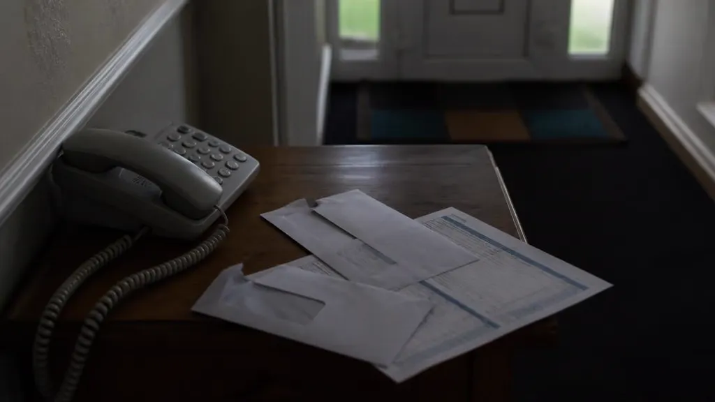 Opened bank envelope and a mortgage statement beside a hallway phone