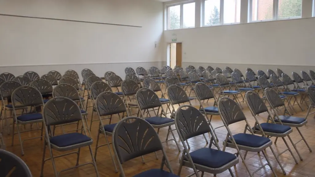 Rows of empty folding chairs in a hall hired for a property auction