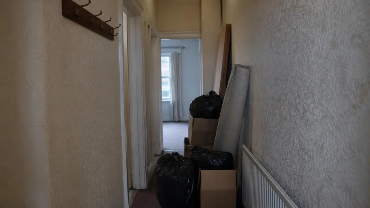 Boxes and bin bags stacked in the hallway of an empty house