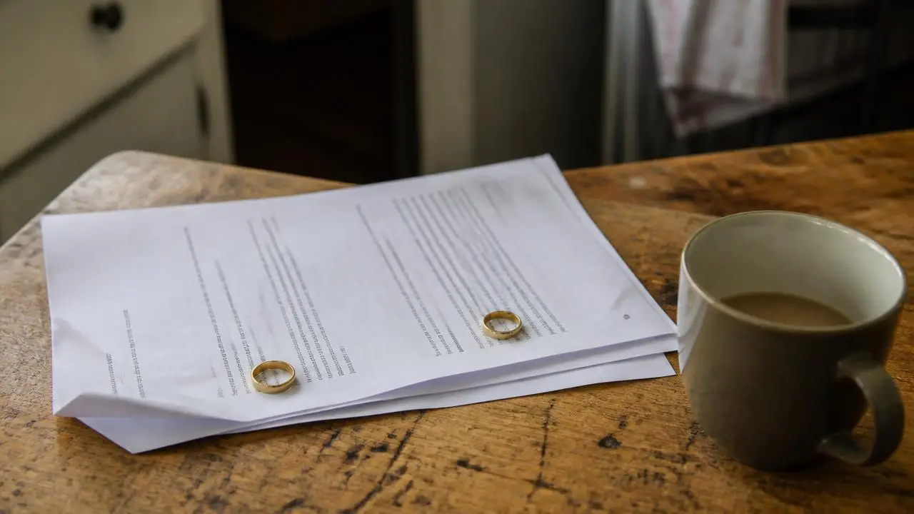 Two wedding rings resting on separation paperwork on a kitchen table