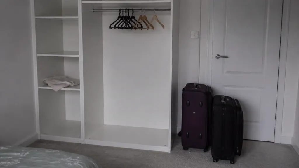 Half-empty wardrobe with two packed suitcases by the bedroom door