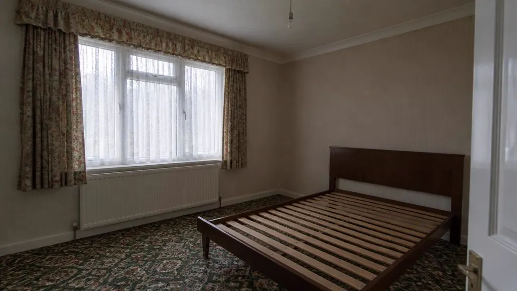 Stripped bed and patterned carpet in a bedroom of an inherited house
