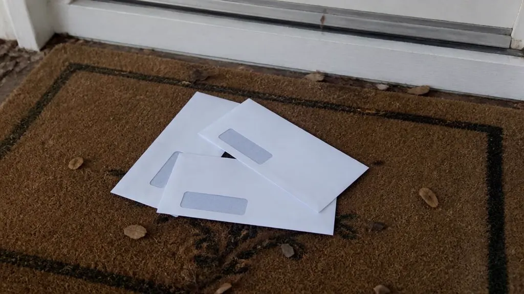 Three unopened window-envelope letters on a doormat inside a front door