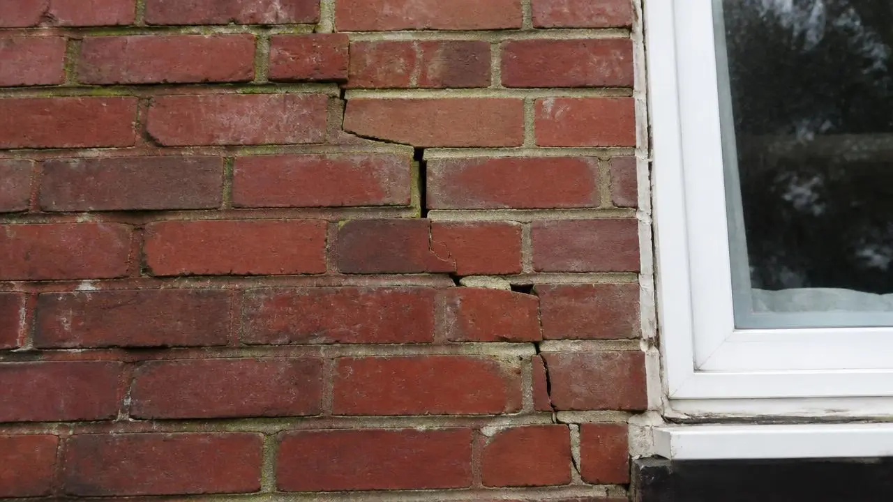Stepped crack running through the brickwork of a house wall