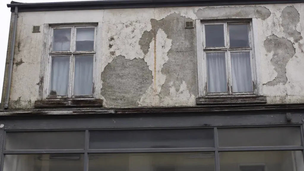 Run-down flat above a shop with peeling render and rotten window frames